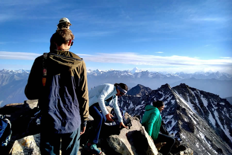 Group of hikers standing on a high-altitude viewpoint, enjoying panoramic mountain views.