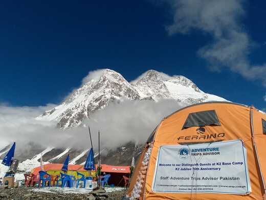 Expedition camp with a signboard and mountains in the background