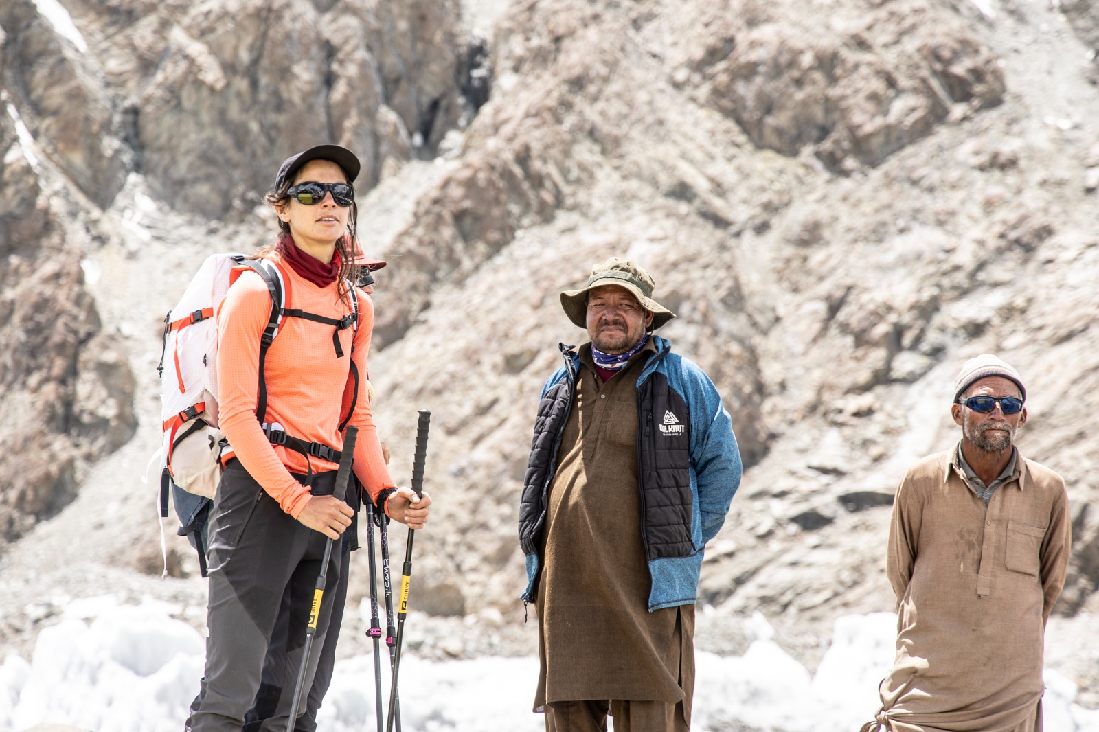 A trekker in deep snow on a high-altitude trail, surrounded by rugged, snow-covered peaks in the Karakoram range.