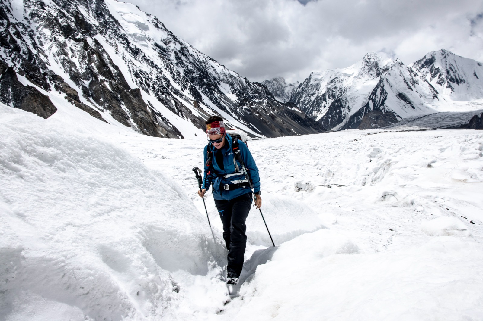 A female trekker wearing sunglasses, a backpack, in the Karakoram Rock climbing adventures of Pakistan.