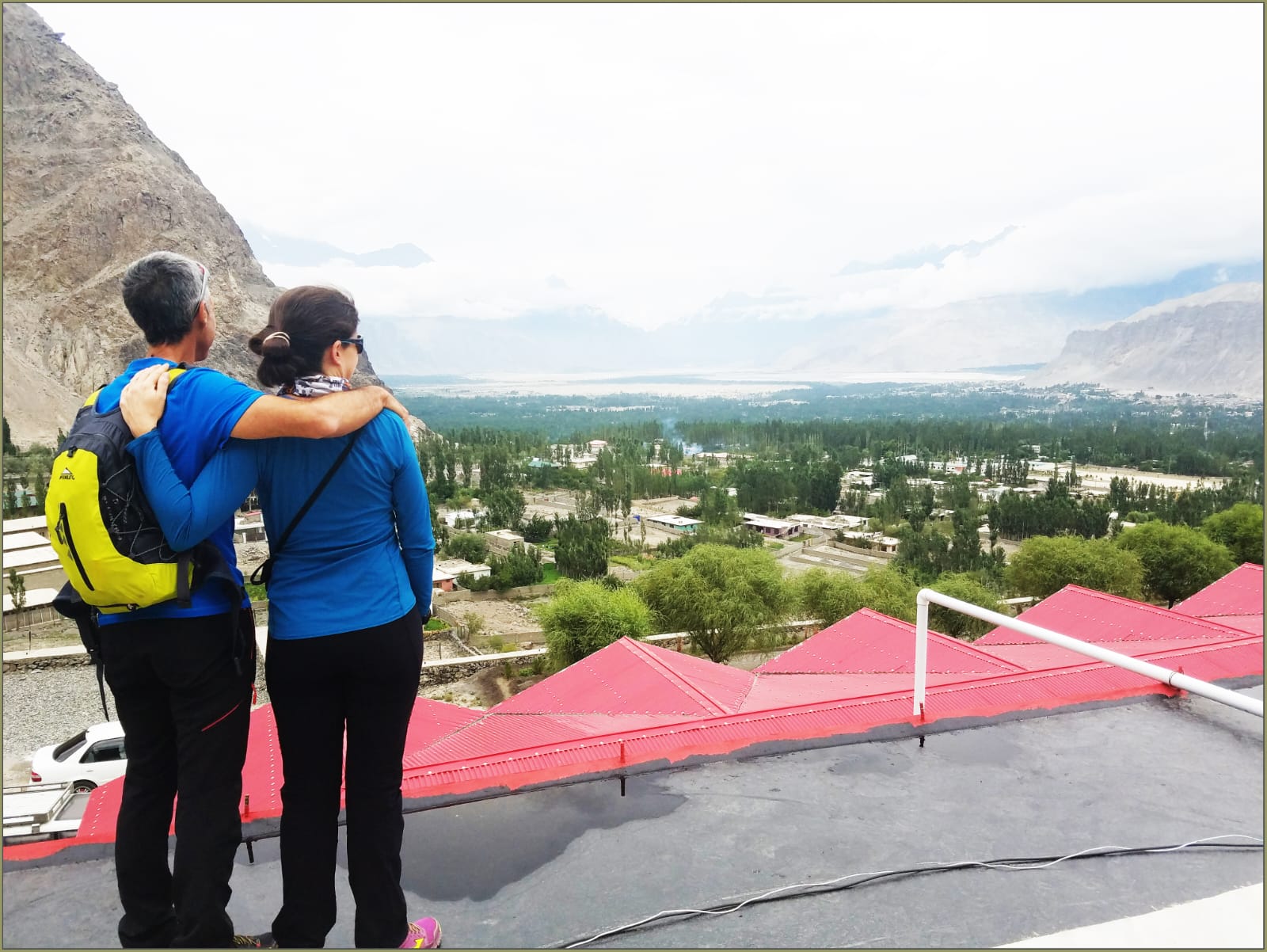 Tourists Enjoying a Scenic View – A group of travelers standing on a red platform with mountains in the background