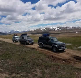 Off-road vehicles driving through a golden-hued landscape, capturing the essence of autumn adventure in Pakistan.