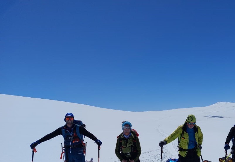 Winter Expedition – Mountaineers trekking on a snow-covered peak under a clear blue sky
